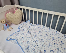 Load image into Gallery viewer, Thin muslin blanket in white with blue dolphins and blue pom pom ribbon