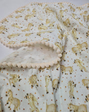Load image into Gallery viewer, Thin muslin blanket in a beige tone with horses and a ribbon of beige pom pom balls