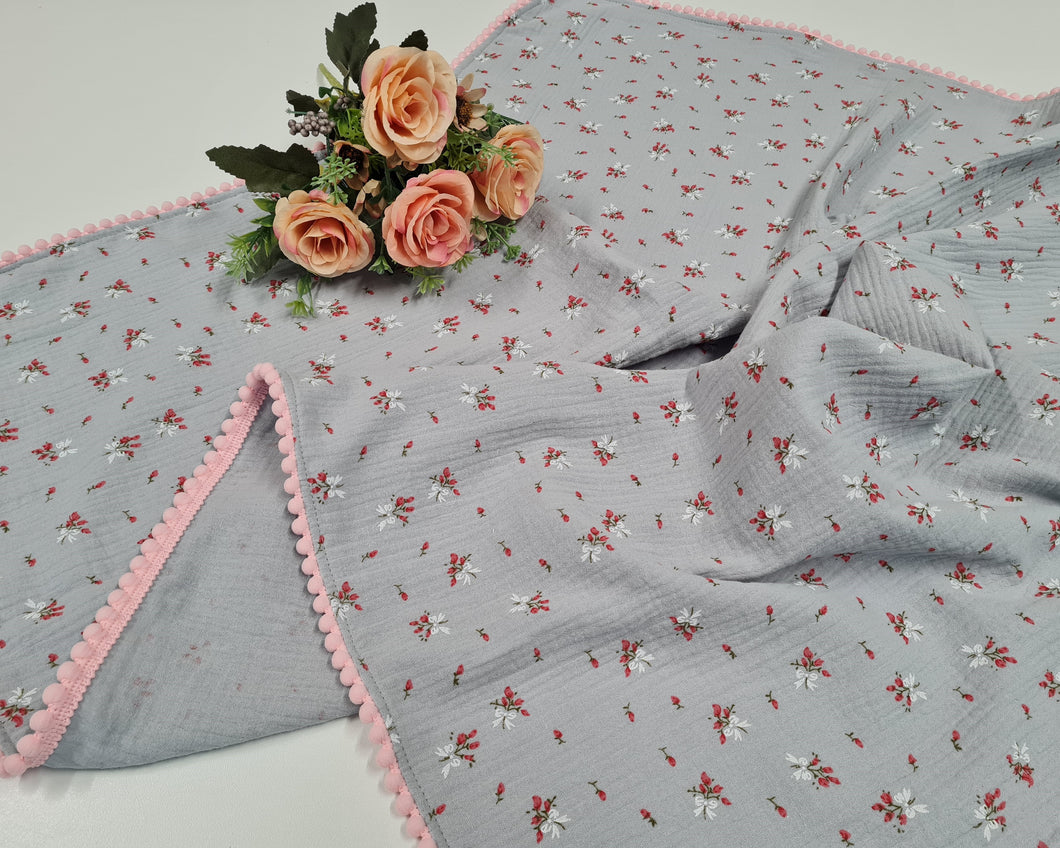 Thin muslin blanket in gray with delicate flowers and pink pom pom ball ribbon