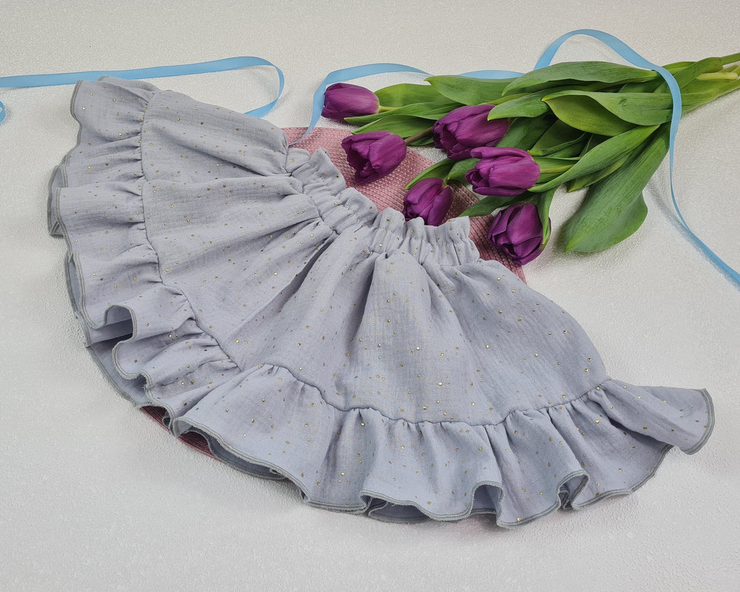 Girls' voluminous skirt with frill made of muslin fabric in a light gray tone with gold dots